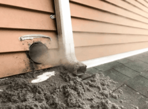 Image of clogged dryer vent with large amounts of old lent ejecting from the vent opening