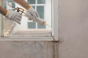 Image of man re-caulking a damaged window casing