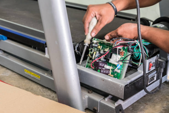 Image of man repairing control board on a treadmill