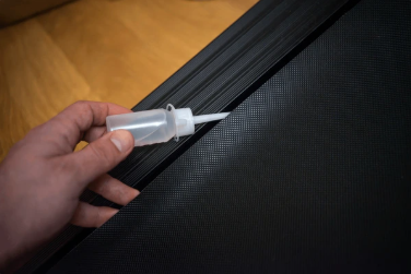 Image of man lubricating the track components of a treadmill