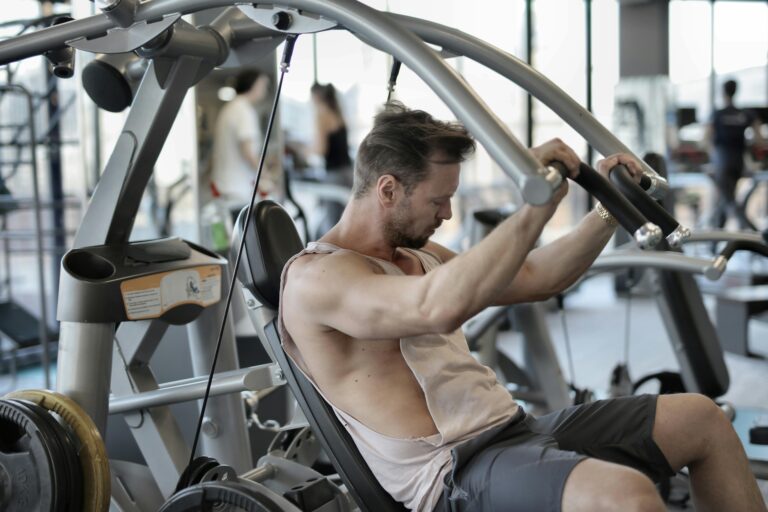 Adult male using gym equipment for strength training, concentrating on exercise indoors.